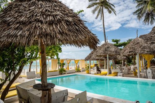 a resort with a swimming pool with straw umbrellas at ZAN Uhuru Jambiani Beach in Bwejuu
