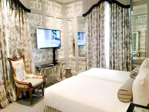 ein Schlafzimmer mit einem Bett, einem Fernseher und einem Stuhl in der Unterkunft Kamiseta Hotel in Camp John Hay