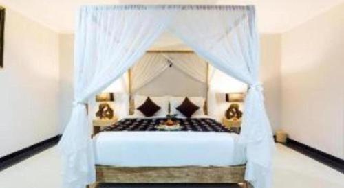 une chambre avec un lit blanc à baldaquin dans l'établissement Evita Villas, à Sukawati