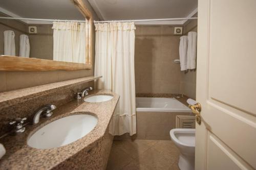 a bathroom with two sinks and a tub and a toilet at Apart Carilo Palace in Carilo