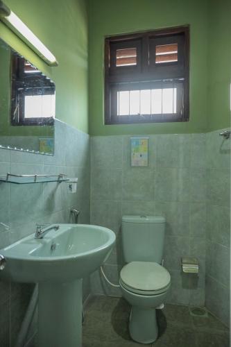 a bathroom with a white toilet and a sink at Self Cate Luxury Apartments in Kandy