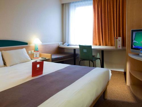 een hotelkamer met een groot bed en een televisie bij ibis Hotel Brussels Airport in Diegem