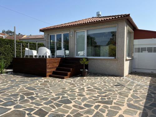 a house with a patio with white chairs on it at Porta da Seca casa con jardín y asador Rías Baixas in Poio
