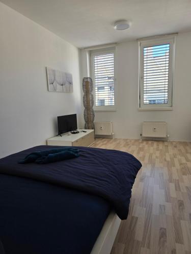 een slaapkamer met een bed en een bureau en twee ramen bij Hotelappartements BR in Fürth