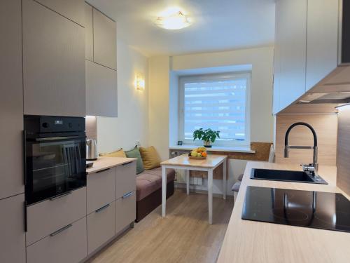 una cucina con mobili bianchi e un tavolo in una stanza di Nidos Laivas a Nida