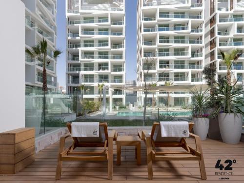 twee stoelen en een tafel op een balkon met een gebouw bij 42 Residence by Brown in Eilat