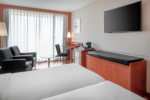 a hotel room with a bed and a flat screen tv at AC Hotel La Rioja by Marriott in Logroño