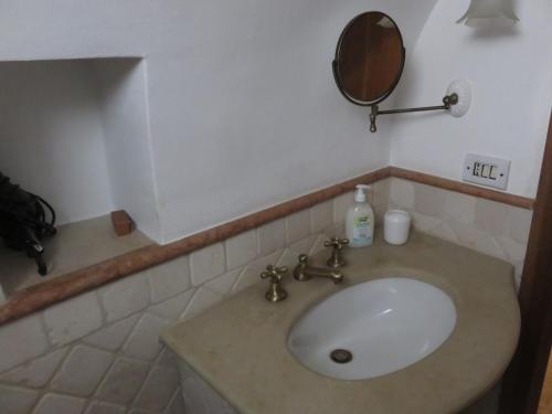 une salle de bain avec un lavabo blanc avec un miroir dans l'établissement Trullo Vacanza, à Alberobello