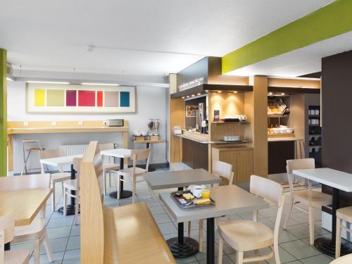un restaurant avec des tables, des chaises et un comptoir dans l'établissement B&B HOTEL Rennes Nord St Grégoire, à Saint-Grégoire