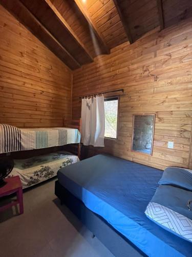 a bedroom with two beds in a wooden cabin at Residencial Bambu in Garopaba