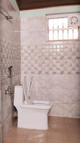 a bathroom with a toilet and a window at WildWood Stay in Madikeri