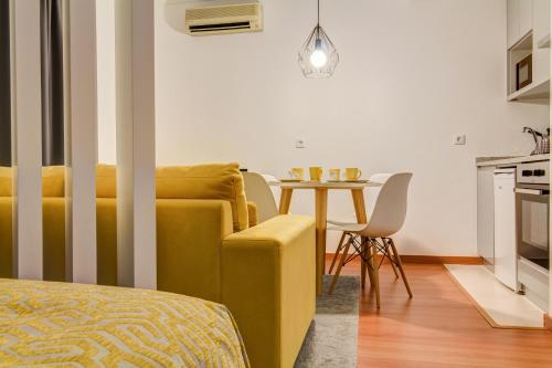 a living room with a yellow couch and a table at Bracara Guest House "Campo Novo" in Braga