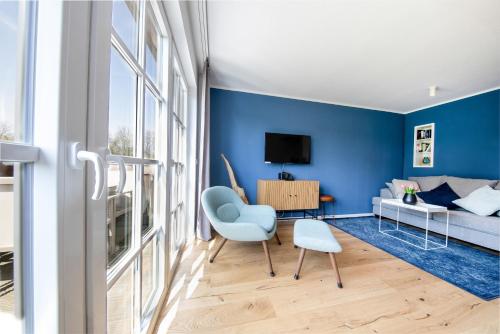 a blue living room with a couch and a chair at Haus an der Düne Wohnung 9 in Lobbe