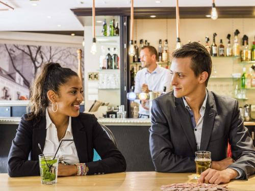 een man en vrouw aan een tafel in een bar bij Mercure Paris Roissy CDG in Roissy-en-France