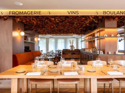 a restaurant with a large wooden table and chairs at Mercure Rouen Centre Champ de Mars in Rouen