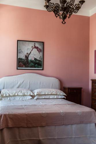 a bedroom with pink walls and a bed with a chandelier at Agriturismo Petrara in Simeri