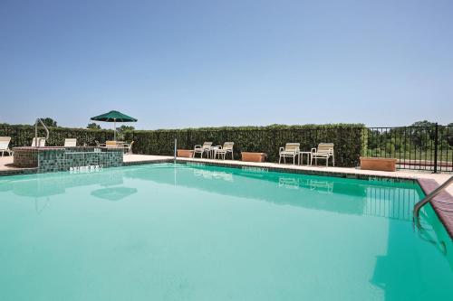 a swimming pool with chairs and an umbrella at Americas Best Value Inn - Gun Barrel City in Gun Barrel City