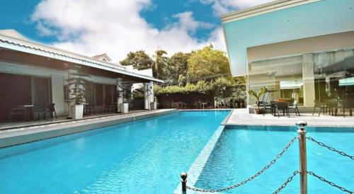 une grande piscine bleue à côté d'une maison dans l'établissement Avenue Suites, à Bacolod