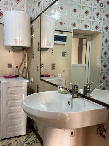 een badkamer met een witte wastafel en een spiegel bij Ali Guest House in Kara-Koo