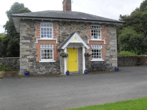 a brick house with a yellow door and a bench at Cloverhill Gate Lodge in Cloverhill