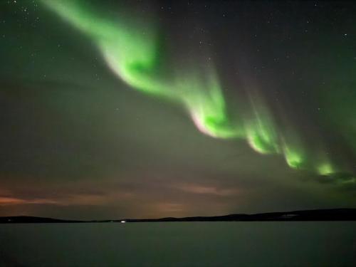 an aurora in the sky over a body of water at Villa Raanujärvi in Romakkaniemi