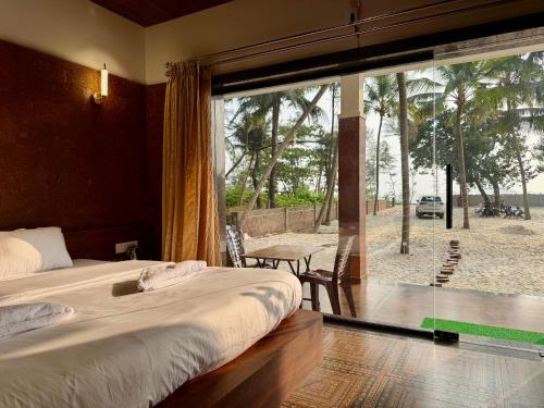 a bedroom with a bed and a large glass window at Navasharada's White Sand Beach House in Udupi