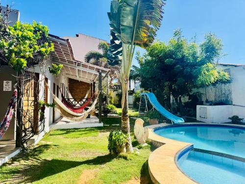 a backyard with a swimming pool and a hammock next to a house at Casa De Praia 9 quartos Em Aguas Belas, CE in Cascavel