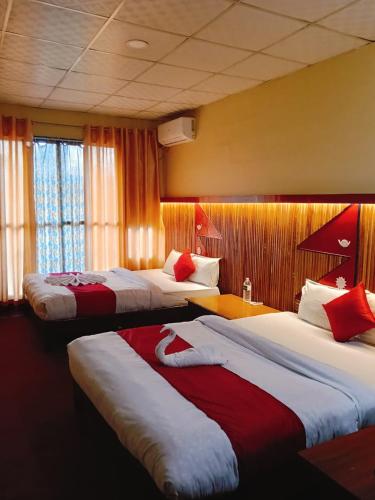 a hotel room with three beds with red and white sheets at Hotel Good one in Pokhara
