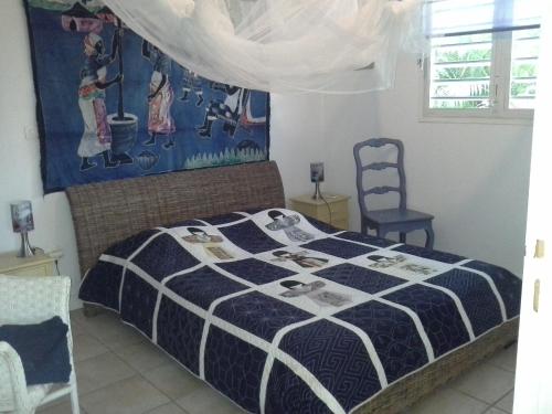 a bedroom with a bed with a blue and white comforter at villa piscine majoma in Sainte-Anne