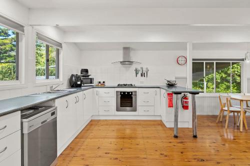 a kitchen with white cabinets and a stove top oven at Mountain Escape Cozy 3-Bedroom Retreat with Outdoor Entertaining in North Tamborine