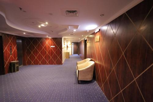 a room with a corridor with a chair and a wall at Maysan AL Multaqa Hotel in Al Masfalah
