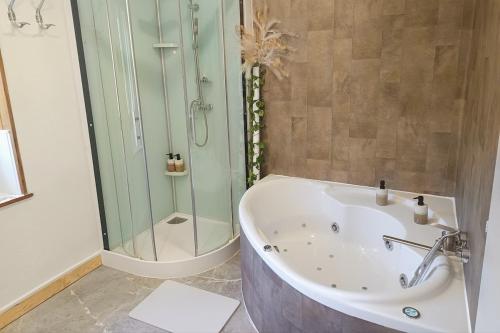a bathroom with a tub and a glass shower at Cap Vosges 3 étoiles, Jeux et Balnéo, entre Vosges et Alsace in Plainfaing