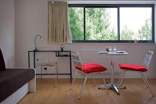 マルク・アン・バルールにあるAppartement Lille Metropolysの椅子2脚、テーブル1台、ベッド1台が備わる客室です。