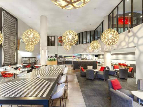 a lobby with tables and chairs and chandeliers at ibis Melbourne Hotel and Apartments in Melbourne