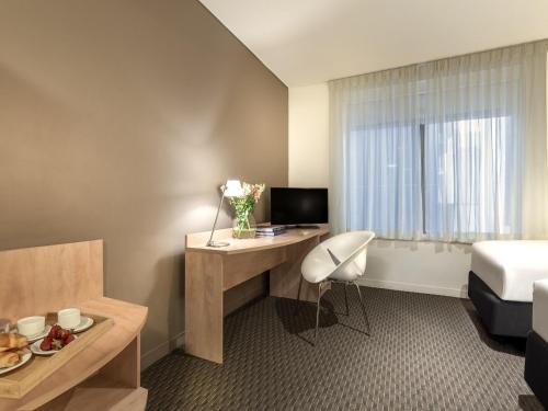 a hotel room with a desk and a bed at ibis Melbourne Hotel and Apartments in Melbourne