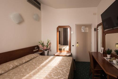 Pokój hotelowy z łóżkiem, biurkiem i lustrem w obiekcie Hotel Centrale w mieście Piombino