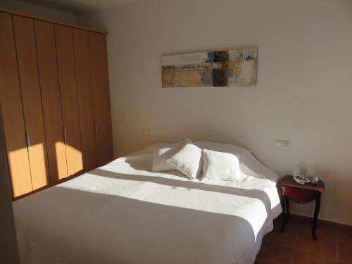 a bedroom with a white bed with a painting on the wall at *Casa Anna L'Atzubia in Adsubia