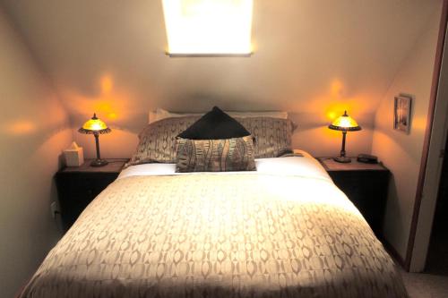 a bedroom with a white bed with two lamps at Cobble Wood and Bird Sanctuary Guest Houses in Tofino