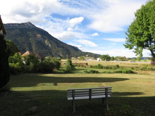 a park bench in a field with a mountain in the background at Hotel Restaurant Le Traineau in Clelles