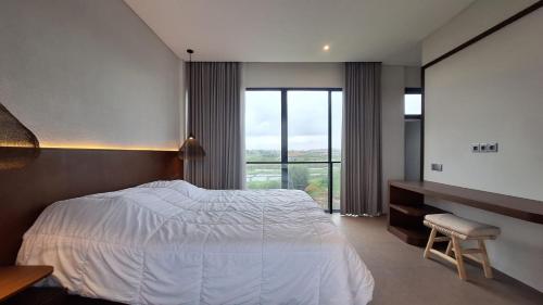 a bedroom with a bed and a desk and a window at Cemagi Beach Hostel by Verdana Pool & Events in Cemagi