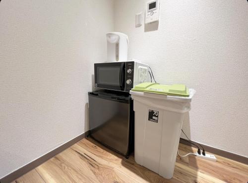 a microwave sitting on top of a counter with a trash can at Sunny Haven in Tokyo in Tokyo