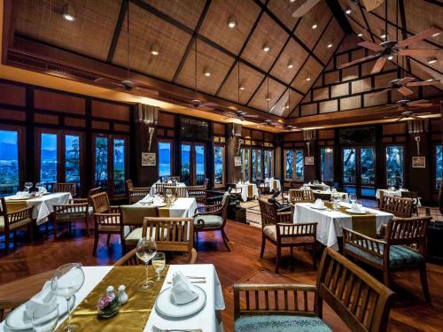a dining room with tables and chairs and windows at Novotel Phuket Resort in Patong Beach