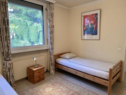 a small bedroom with a bed and a window at Portofino by Fewotessin in Brissago
