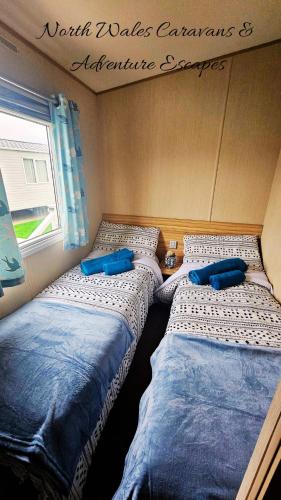 three beds sitting in a room with a window at Park Dean Resorts Premium plot with Mountain view & Decking in Abergele
