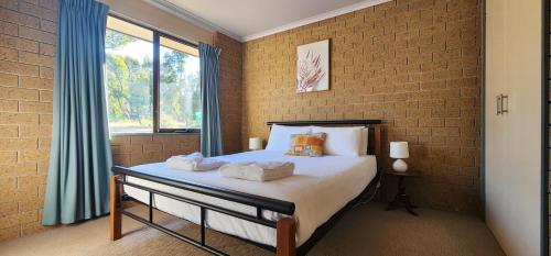 a bedroom with a bed and a brick wall at Pomonal Cottages Grampians in Halls Gap