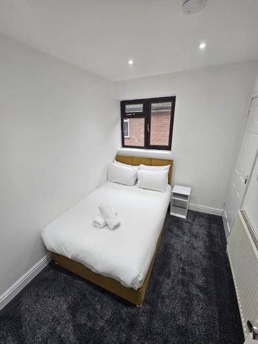 a bedroom with a bed with white sheets and a window at Moor Layover Heathrow - Cozy Crew Stay - 10 min to Airport in Harmondsworth