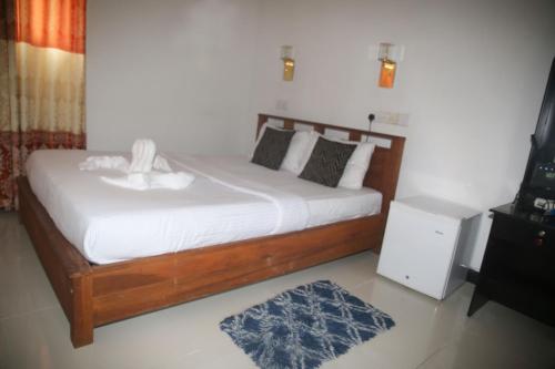 ein Schlafzimmer mit einem Bett mit weißer Bettwäsche und einem blauen Teppich in der Unterkunft Rivinu Holiday Resort in Ella