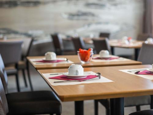 een rij houten tafels met hoeden en servetten bij Mercure Vannes Le Port in Vannes