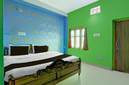 een slaapkamer met een bed met blauwe en groene muren bij Hotel O by OYO Fakir Guest House in Puri