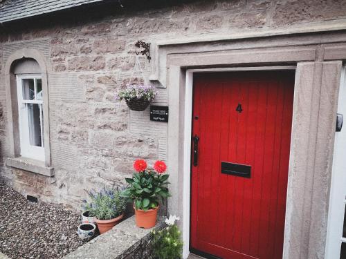 a red door on the side of a brick house at Woodview Cottage in Glamis